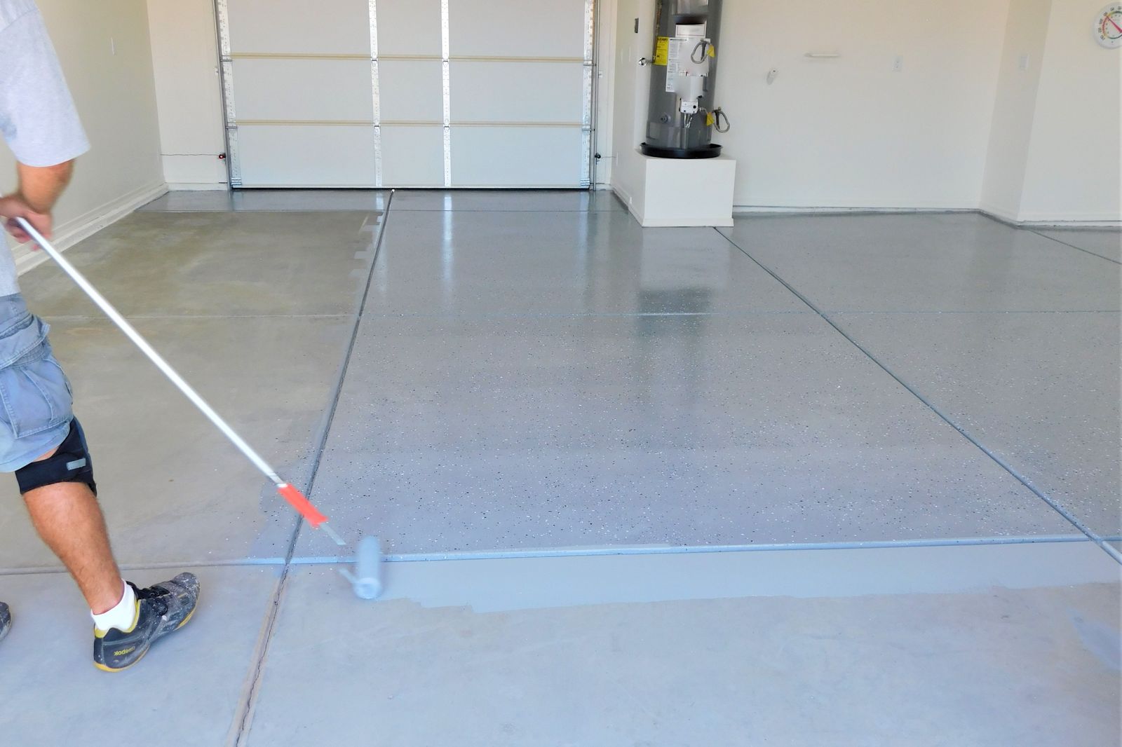 Installer rolling a floor coating across a garage slab